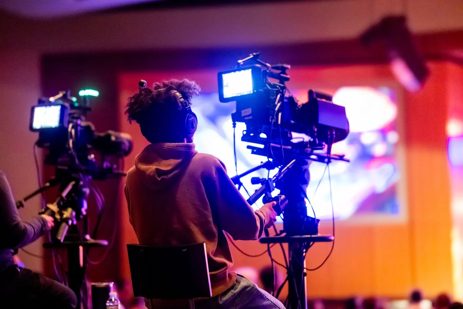 A camera operator filming a worship service for the live stream, seen from behind